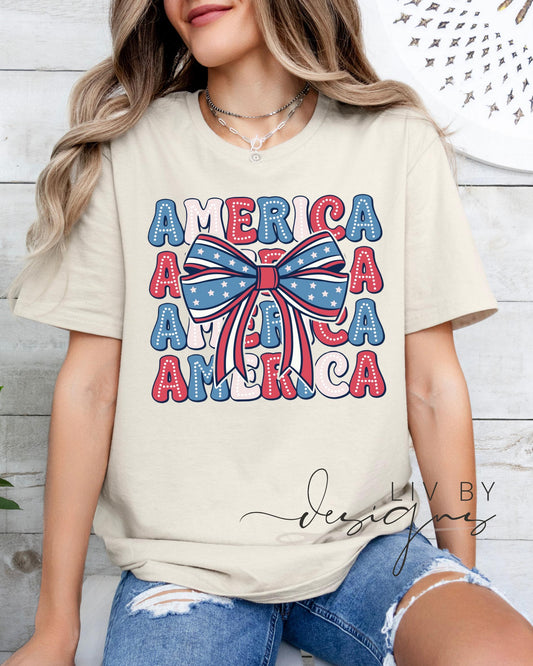 “Woman in ivory Comfort Colors tee with America text and patriotic bow design”