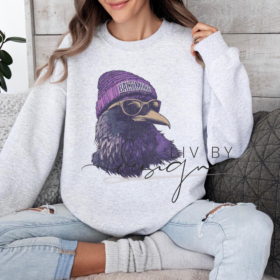 Baltimore football crewneck sweatshirt with raven wearing purple beanie and sunglasses
