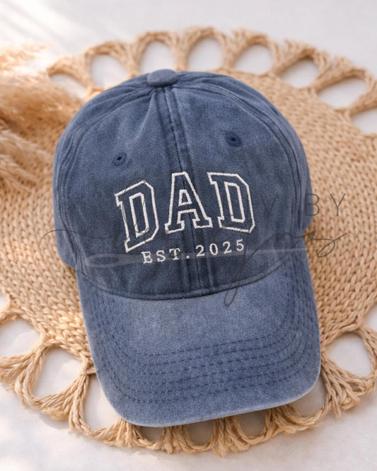 Single Ball Cap with adjustable strap featuring an embroidered DAD est date logo - placed on a woven placemat for photo