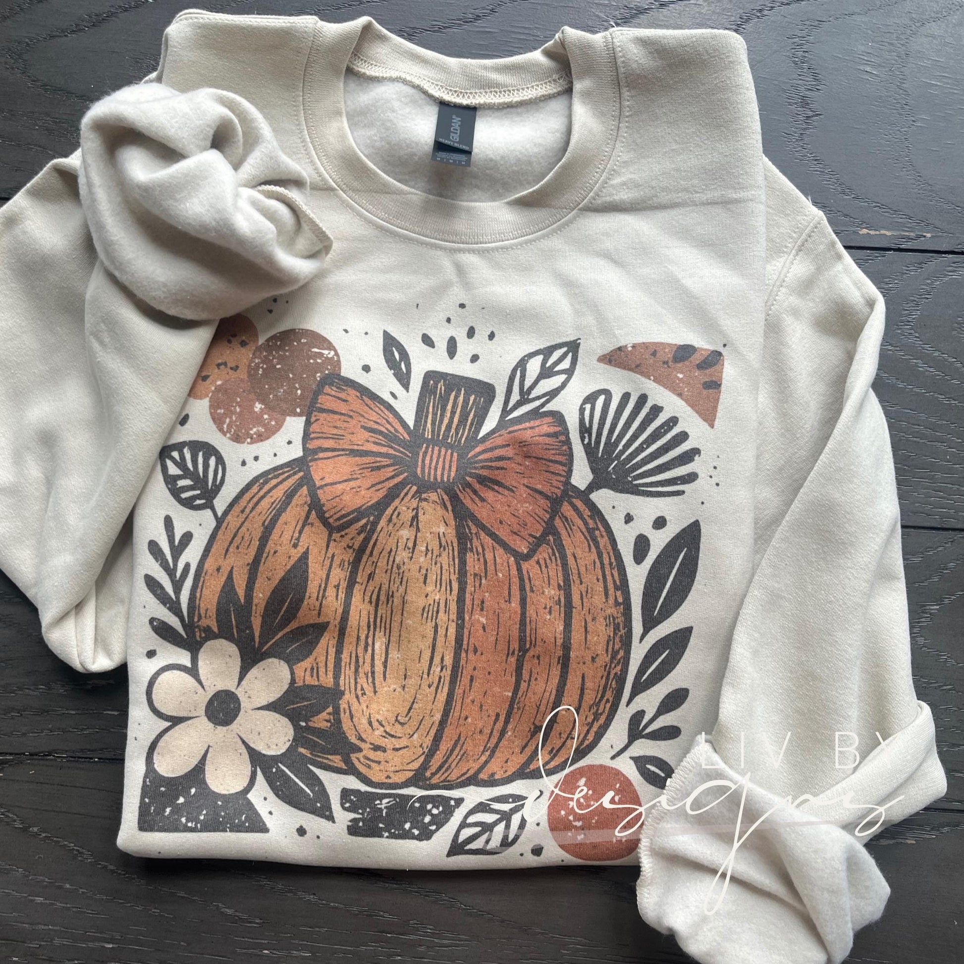 Sublimated Gildan crewneck with pumpkin bow design on sand color sweatshirt